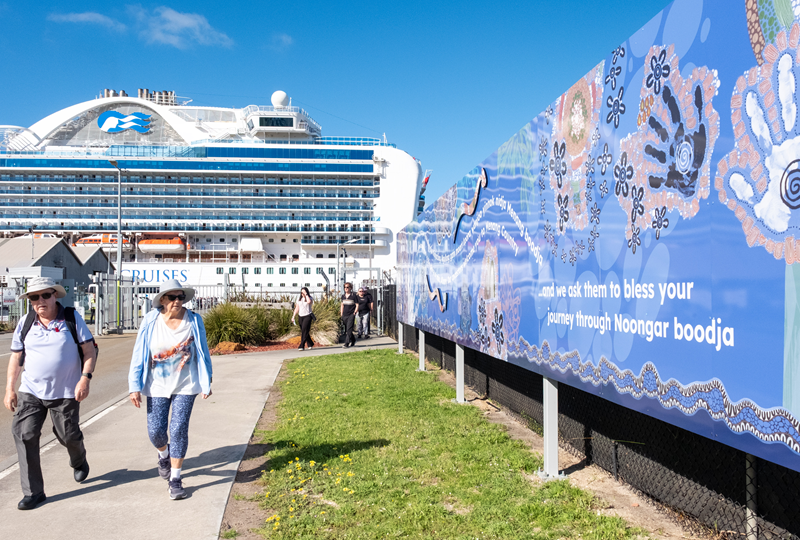 Cruise passengers walking by cruise welcome sign