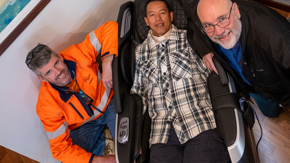 Southern Ports General Manager South West Marty Stafford and Bunbury Mission to Seafarers Centre Managers Very Rev. Darryl Cotton check out the new massage chair donated to Bunbury MTS as centre chaplain Reverend Gaerlan Baguil test the chair.
