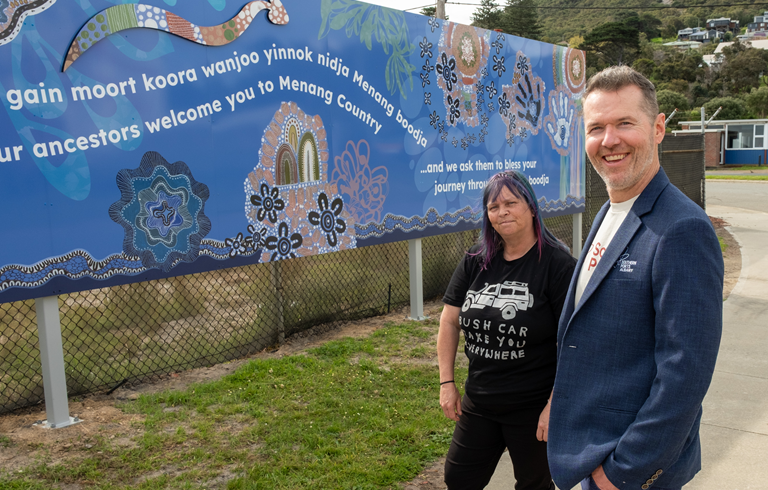 Merningar artist Shandell Cummings and Southern Ports Acting General Manager - Great Southern Paul Mackey in front of the Port of Albany cultural welcome sign based on Shandell's artwork.