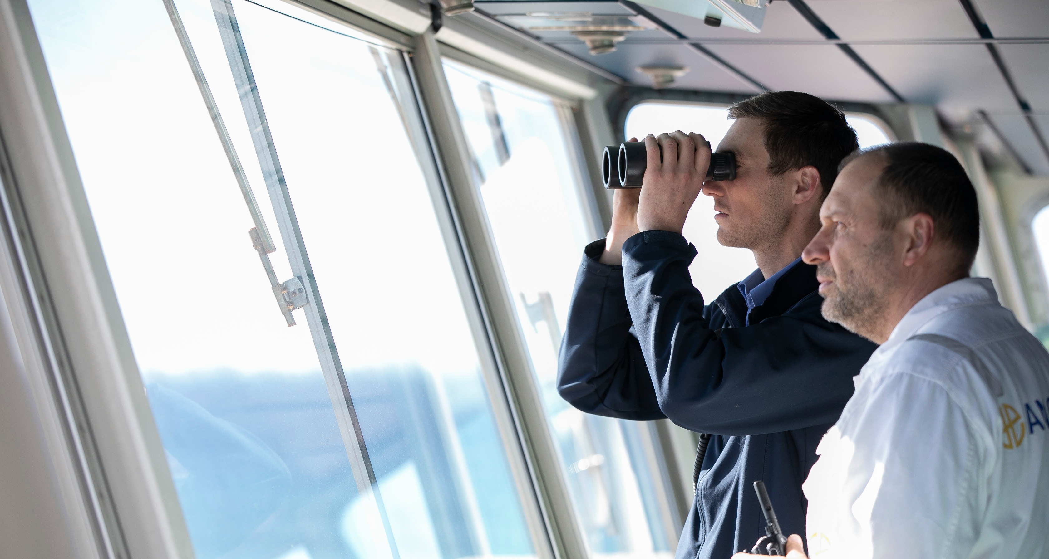 Marine pilot on vessel looking out with binoculars