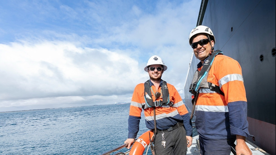 Two deckhands on a pilot boat alongside a vessel